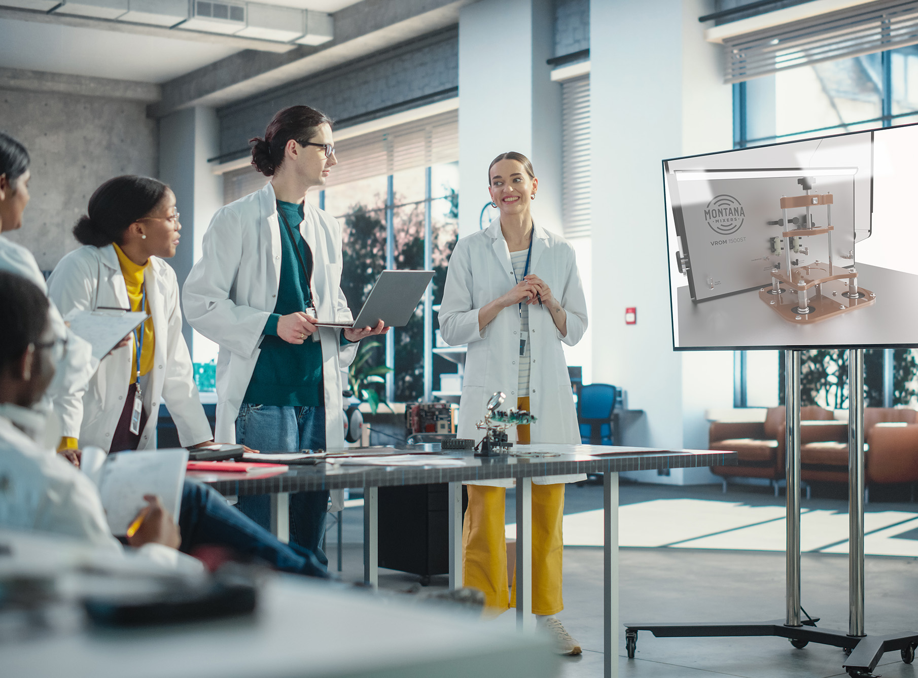 A group of college students looks at a resonant mixer on a large flat screen monitor
